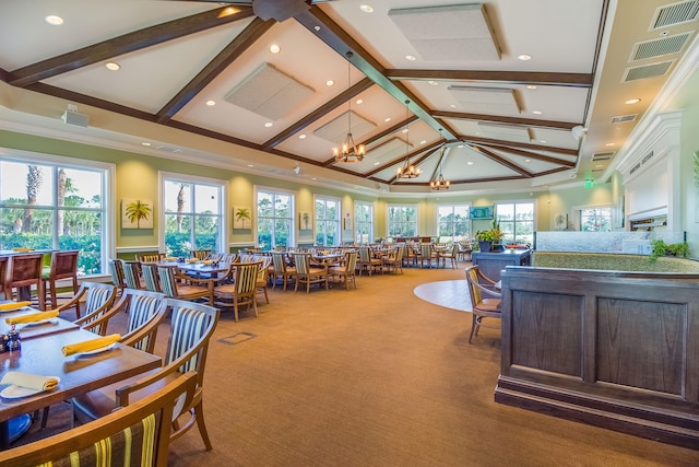 interior space featuring ceiling fan with notable chandelier, high vaulted ceiling, beamed ceiling, and plenty of natural light