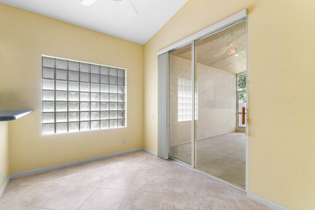 unfurnished bedroom with ceiling fan, light tile patterned flooring, a closet, and vaulted ceiling