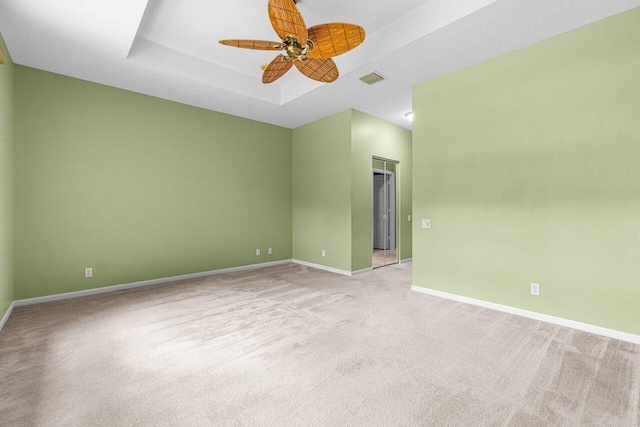 carpeted spare room featuring a tray ceiling, ceiling fan, and a textured ceiling