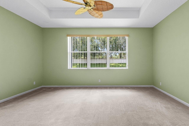 spare room featuring carpet, ceiling fan, and a raised ceiling