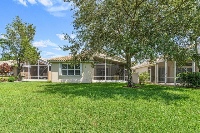 rear view of property with a lawn and a lanai