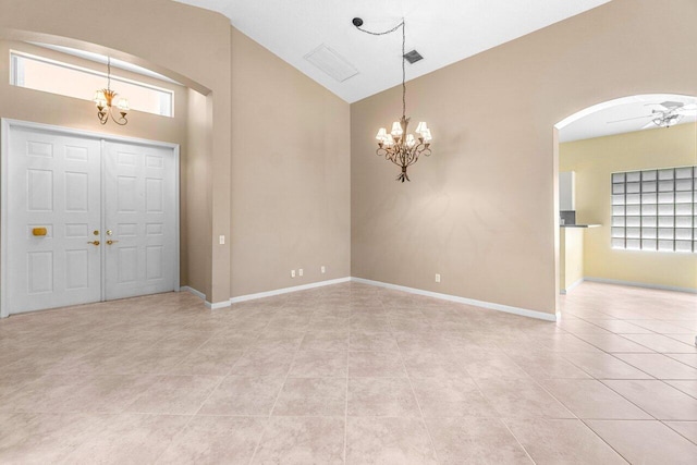 tiled entrance foyer featuring ceiling fan with notable chandelier and high vaulted ceiling