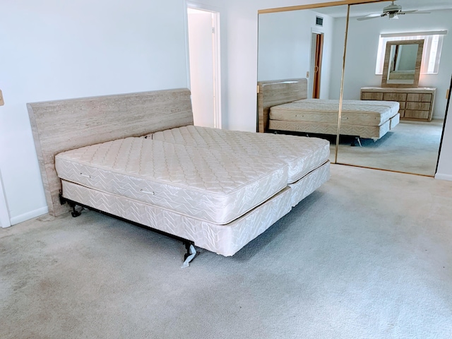 bedroom featuring light colored carpet, ceiling fan, and a closet