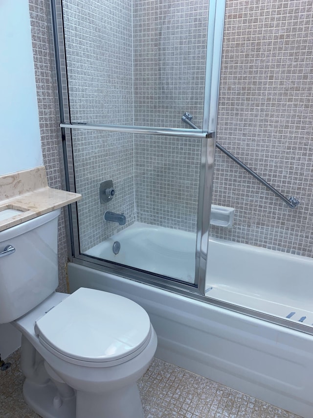 full bathroom featuring tile patterned flooring, vanity, shower / bath combination with glass door, and toilet