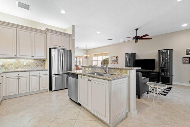 kitchen with sink, a center island with sink, appliances with stainless steel finishes, light tile patterned floors, and decorative light fixtures