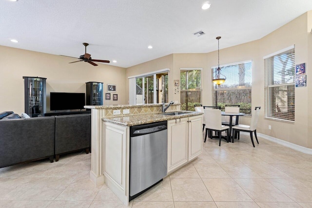 kitchen with hanging light fixtures, light stone counters, dishwasher, a kitchen island with sink, and sink