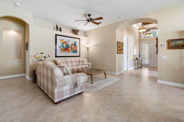 living room with a textured ceiling, ceiling fan with notable chandelier, and light tile patterned flooring