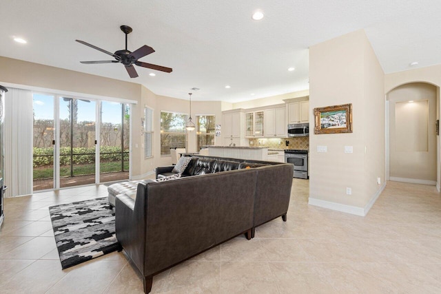 tiled living room with a textured ceiling and ceiling fan with notable chandelier