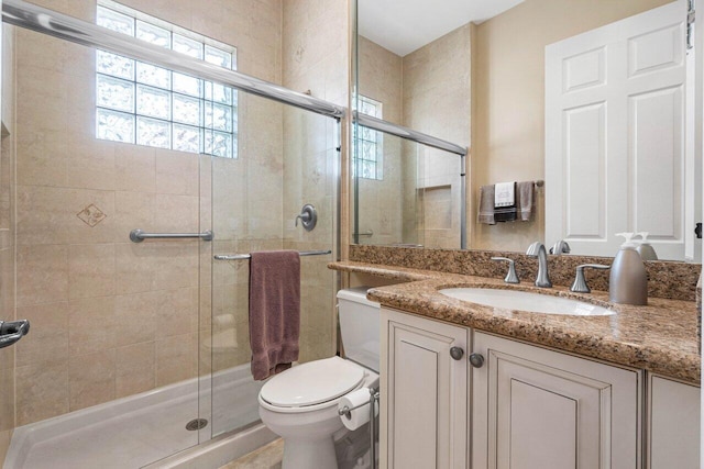 bathroom featuring a shower with door, vanity, and toilet