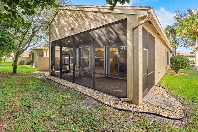 rear view of house featuring a lawn and a sunroom