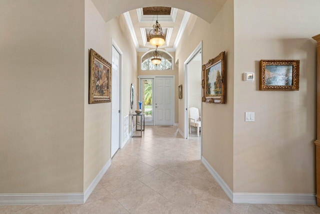 corridor featuring light tile patterned floors, crown molding, and a chandelier