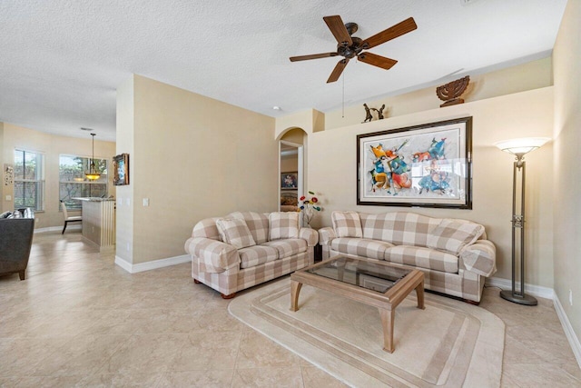 tiled living room featuring ceiling fan and a textured ceiling