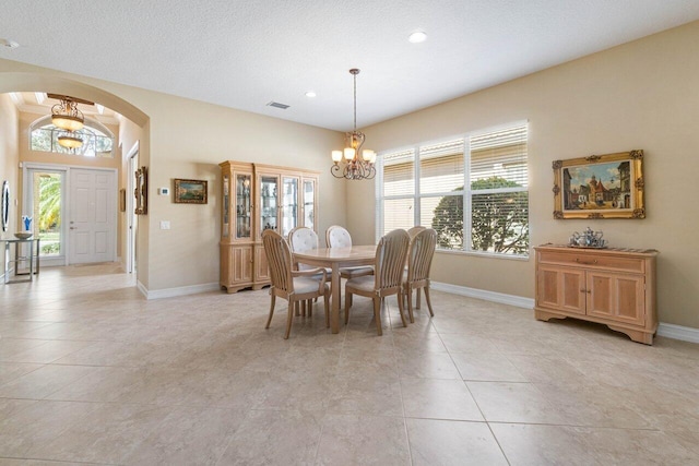 tiled dining room featuring a notable chandelier and a textured ceiling