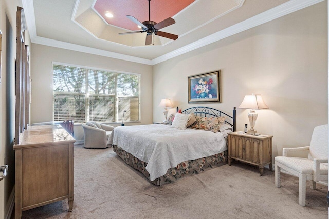 carpeted bedroom with a tray ceiling, ceiling fan, and crown molding