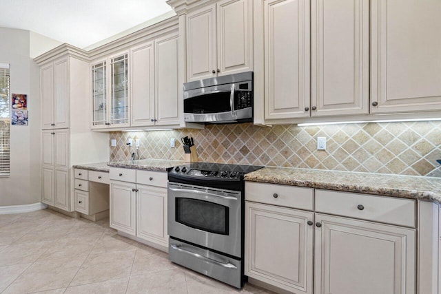 kitchen with stainless steel appliances, backsplash, light stone counters, and light tile patterned floors