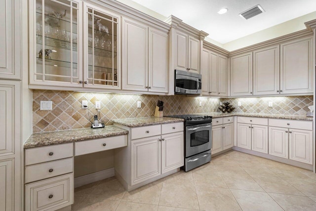 kitchen featuring light stone countertops, appliances with stainless steel finishes, backsplash, and light tile patterned floors