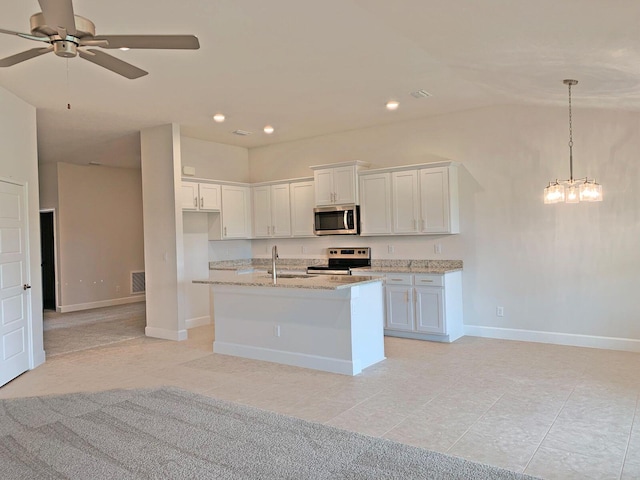 kitchen featuring light stone countertops, a kitchen island with sink, stainless steel appliances, white cabinets, and ceiling fan with notable chandelier