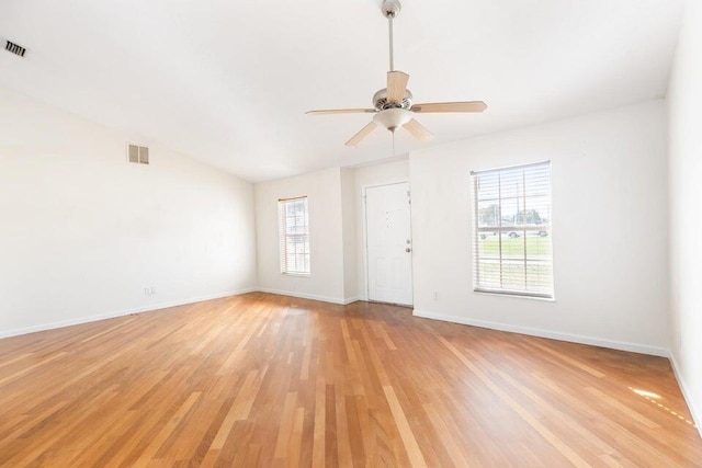 empty room featuring plenty of natural light, vaulted ceiling, ceiling fan, and light hardwood / wood-style flooring