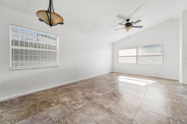 unfurnished room featuring a textured ceiling, a wealth of natural light, ceiling fan, and vaulted ceiling