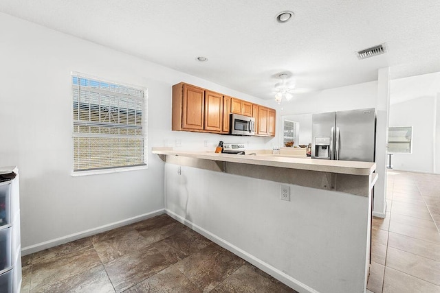 kitchen with ceiling fan, kitchen peninsula, stainless steel appliances, and a breakfast bar