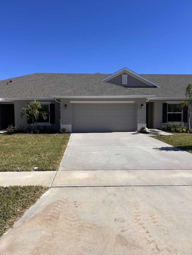 ranch-style house featuring a garage and a front lawn