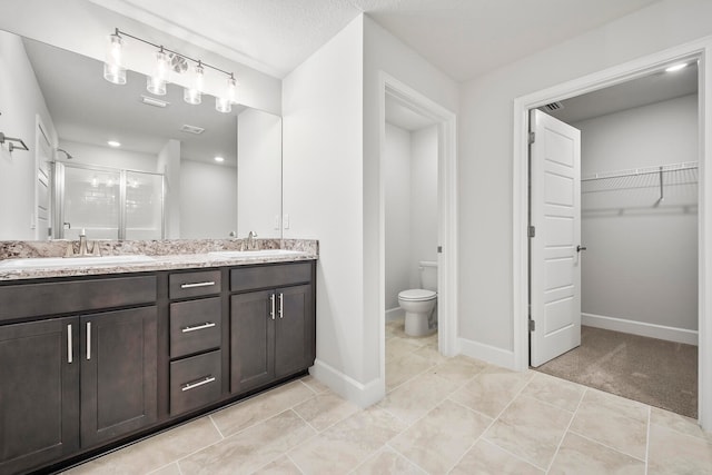 bathroom featuring tile patterned flooring, vanity, toilet, and an enclosed shower