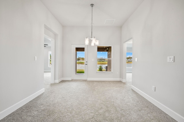 carpeted empty room featuring ceiling fan with notable chandelier