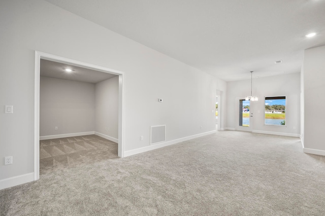 unfurnished living room featuring light carpet and a chandelier