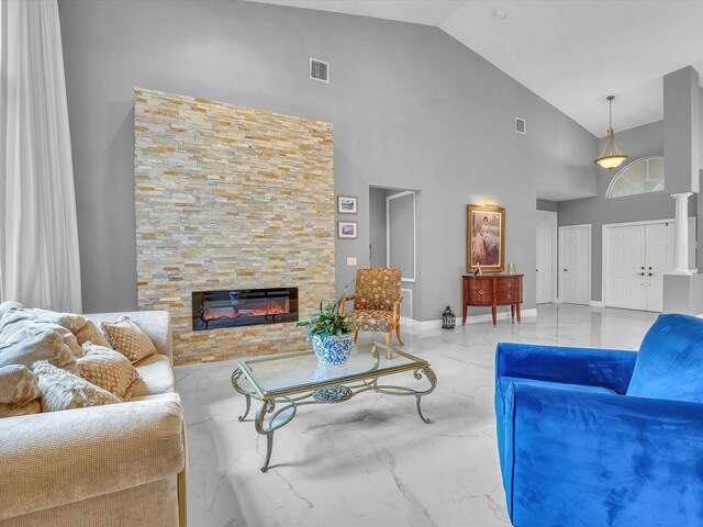 living room with a stone fireplace and high vaulted ceiling