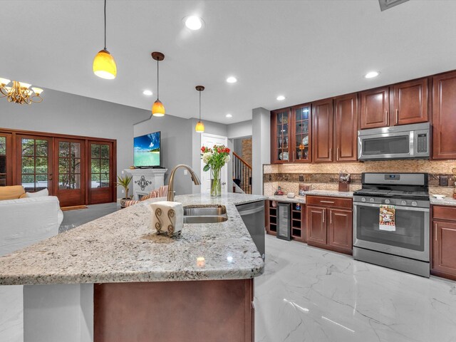 kitchen featuring stainless steel appliances, sink, hanging light fixtures, beverage cooler, and decorative backsplash