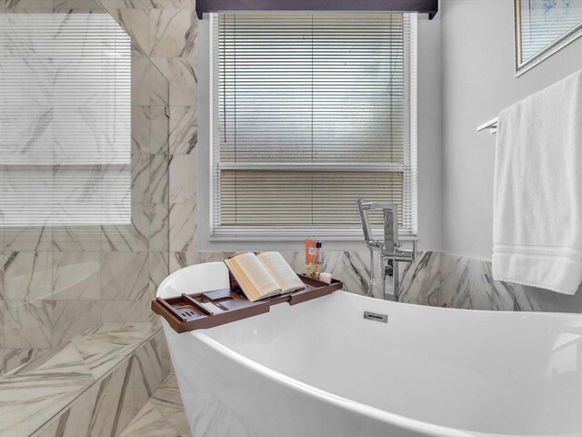 bathroom with a bathing tub and tile walls