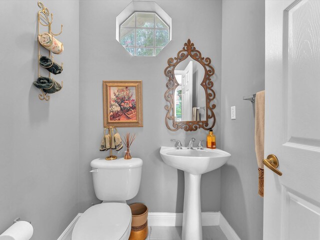 bathroom with toilet, sink, tile patterned flooring, and plenty of natural light