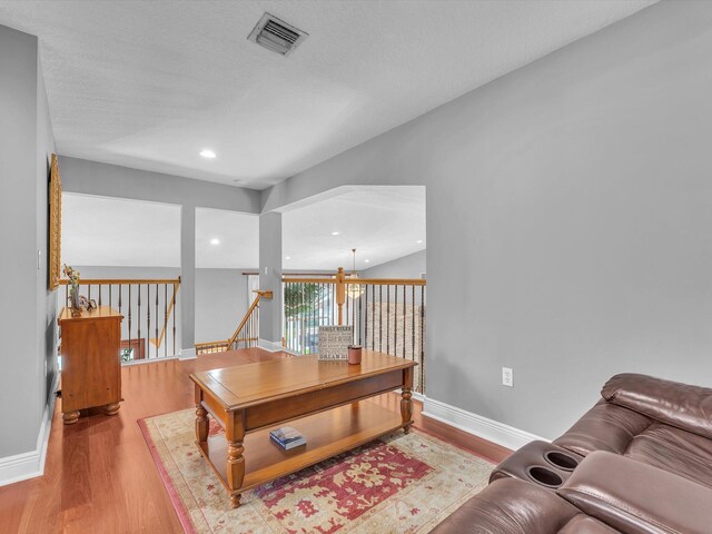 living room with light hardwood / wood-style flooring, a textured ceiling, and an inviting chandelier