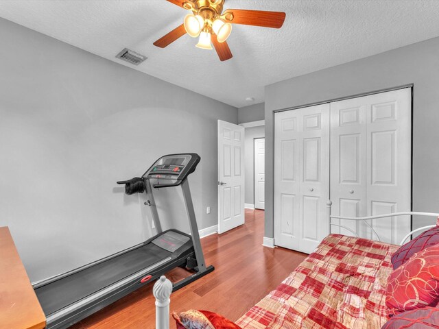 workout room with hardwood / wood-style flooring, ceiling fan, and a textured ceiling