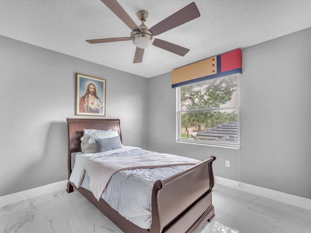 bedroom with ceiling fan and a textured ceiling