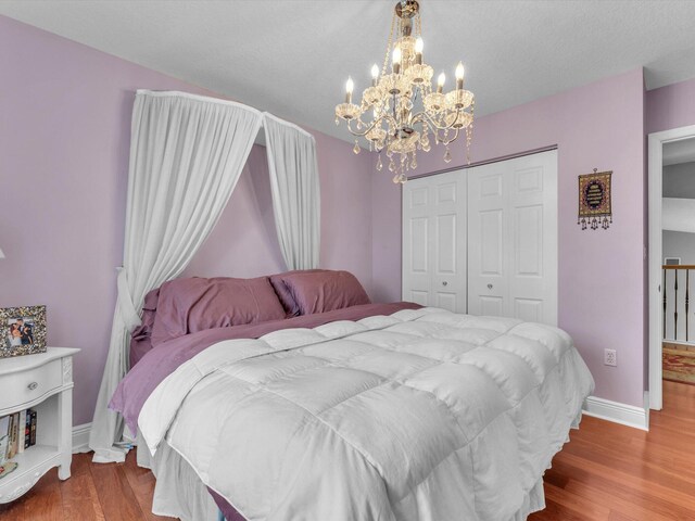 bedroom with light wood-type flooring, a textured ceiling, a closet, and an inviting chandelier