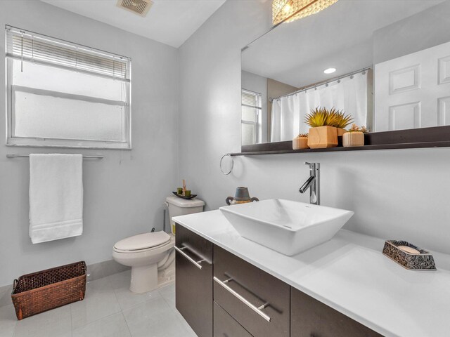 bathroom with vanity, curtained shower, tile patterned flooring, and toilet