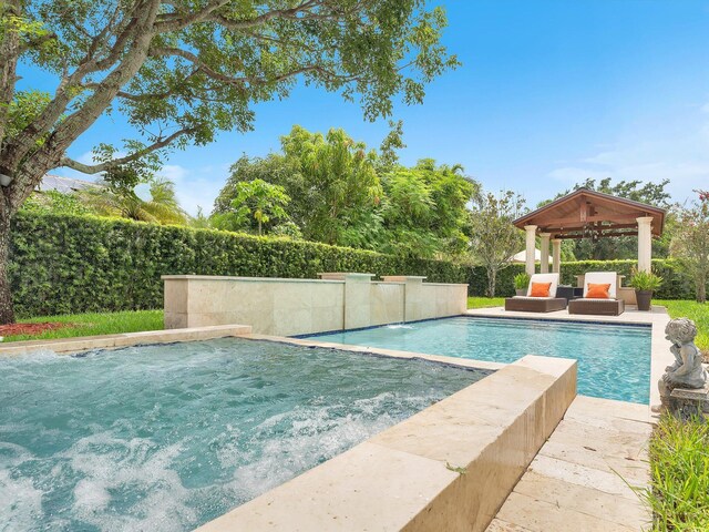 view of swimming pool featuring ceiling fan, a gazebo, and pool water feature