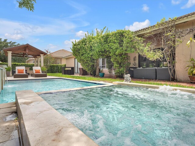 view of swimming pool with ceiling fan, pool water feature, and a gazebo