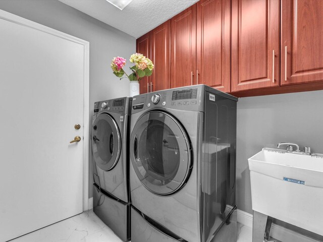 laundry room with washer and clothes dryer, cabinets, sink, and a textured ceiling