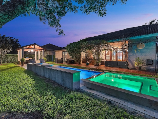 pool at dusk featuring a gazebo, a patio, an in ground hot tub, and a yard