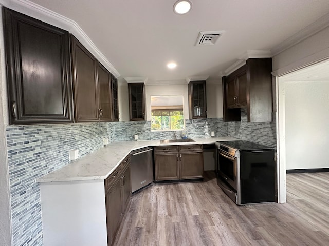 kitchen with appliances with stainless steel finishes, crown molding, sink, and light hardwood / wood-style flooring