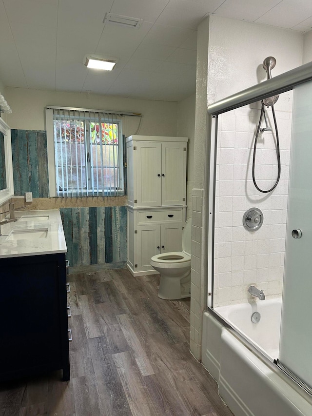 full bathroom with vanity, shower / bath combination with glass door, hardwood / wood-style floors, and toilet