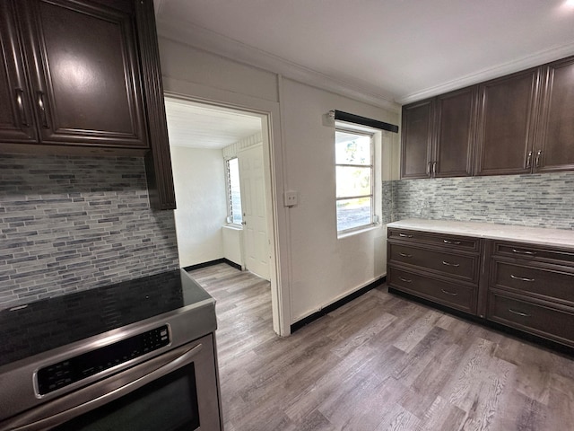 kitchen featuring dark brown cabinetry, stainless steel range with electric stovetop, and light wood-type flooring