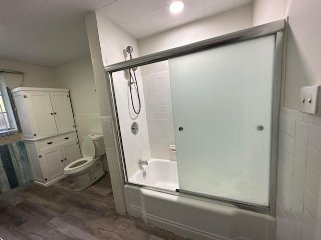 bathroom featuring enclosed tub / shower combo, tile walls, toilet, and hardwood / wood-style flooring