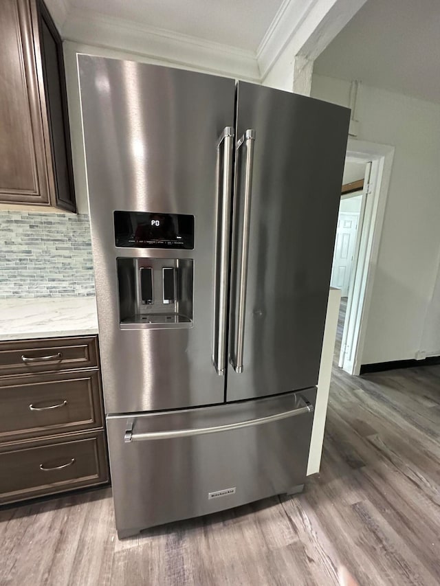 interior space with ornamental molding, dark brown cabinets, backsplash, stainless steel refrigerator with ice dispenser, and light hardwood / wood-style floors