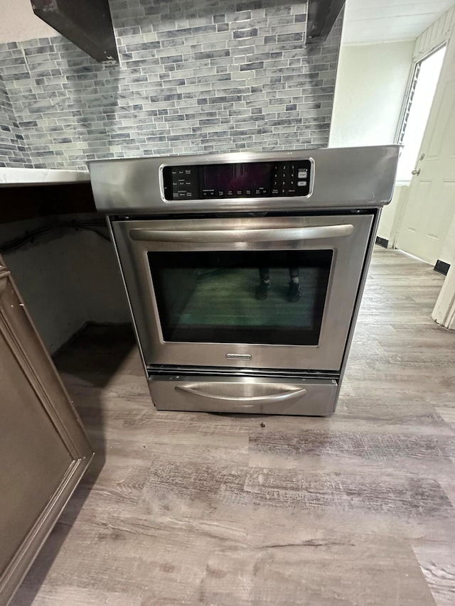 interior details with stainless steel range, light hardwood / wood-style floors, and decorative backsplash