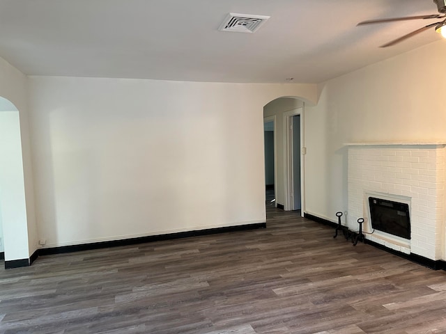 unfurnished living room with ceiling fan, a fireplace, and dark hardwood / wood-style flooring