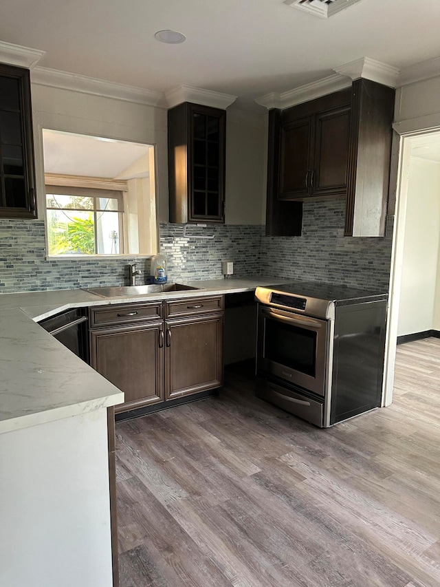 kitchen with dark brown cabinets, light hardwood / wood-style floors, decorative backsplash, stainless steel appliances, and crown molding