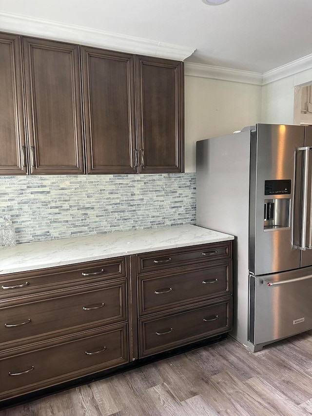 kitchen featuring light hardwood / wood-style floors, stainless steel fridge with ice dispenser, backsplash, dark brown cabinetry, and crown molding